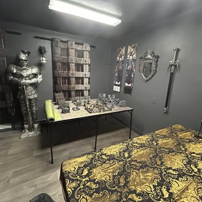 Salle médiévale du Repaire avec armure de chevalier et figurines Warhammer